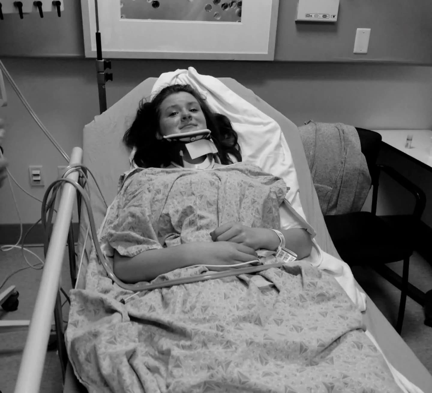 Cassidy as a young patient in the hospital, smiling in a neck brace
